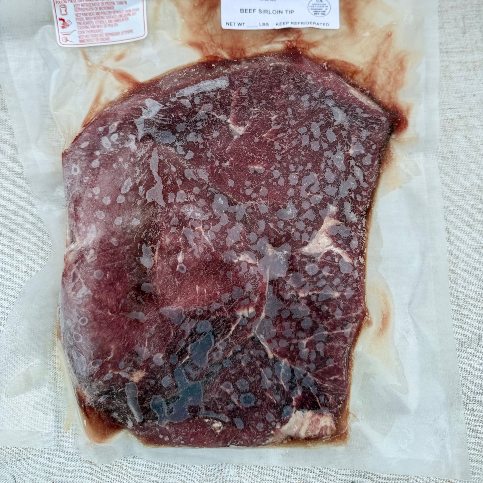 Raw beef steak on a white paper with labels on a textured beige background