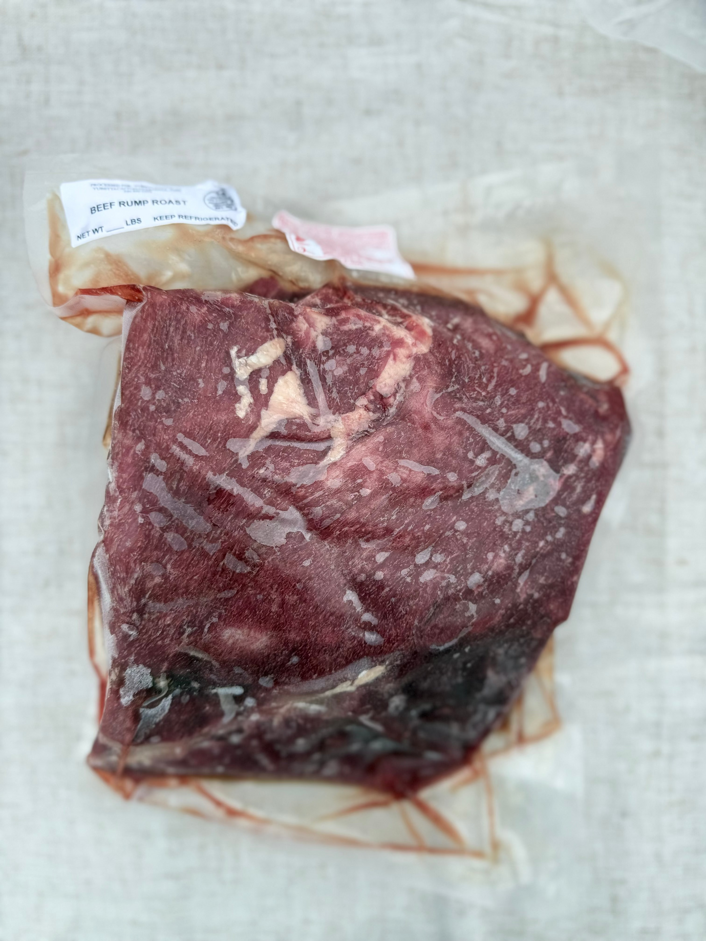 Vacuum-sealed raw meat package on a light fabric background