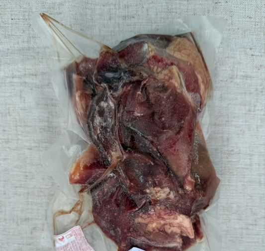 Vacuum-sealed package of beef cheek meat on a textured surface
