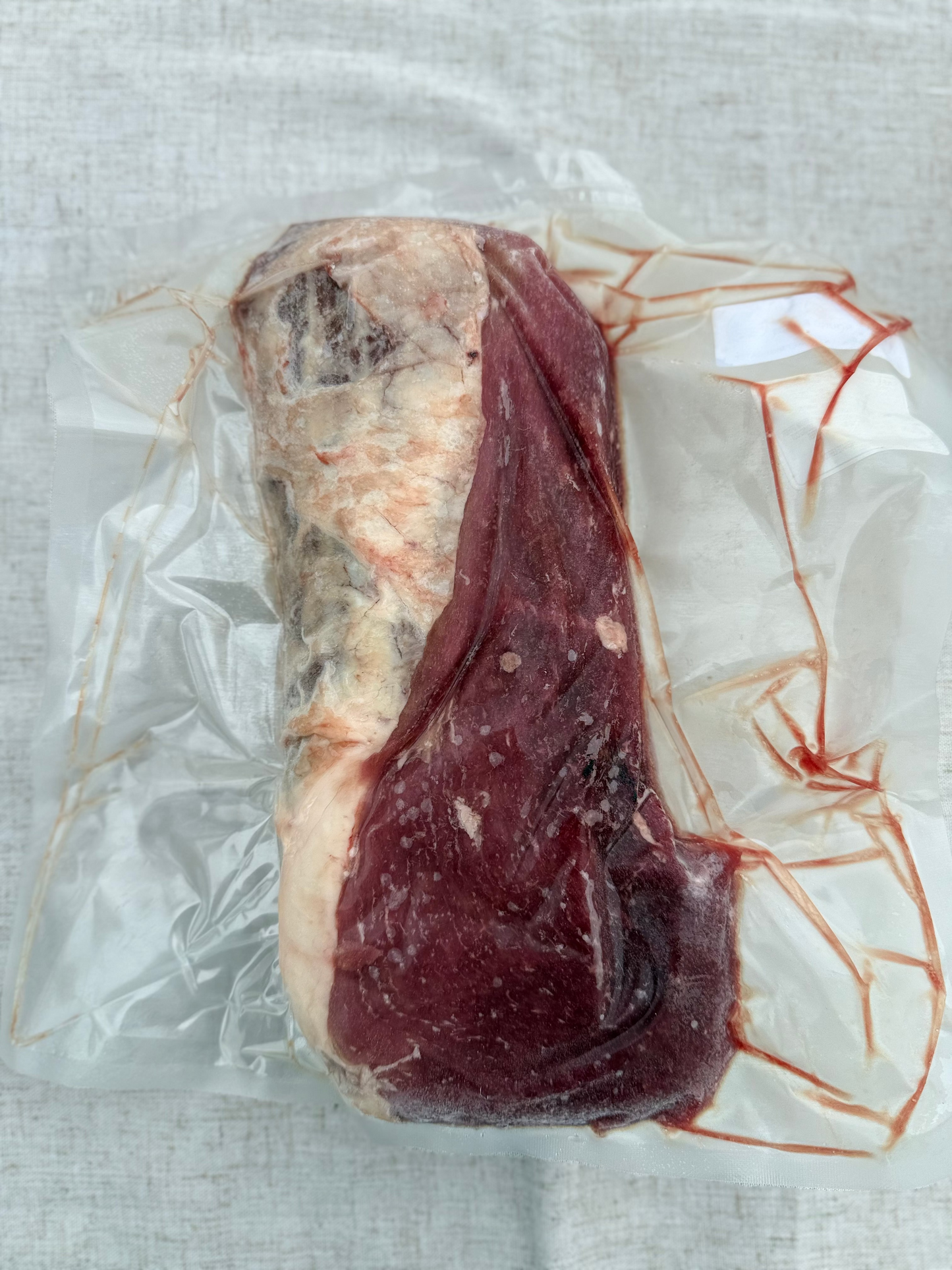 Vacuum-sealed package of raw meat on a textured surface