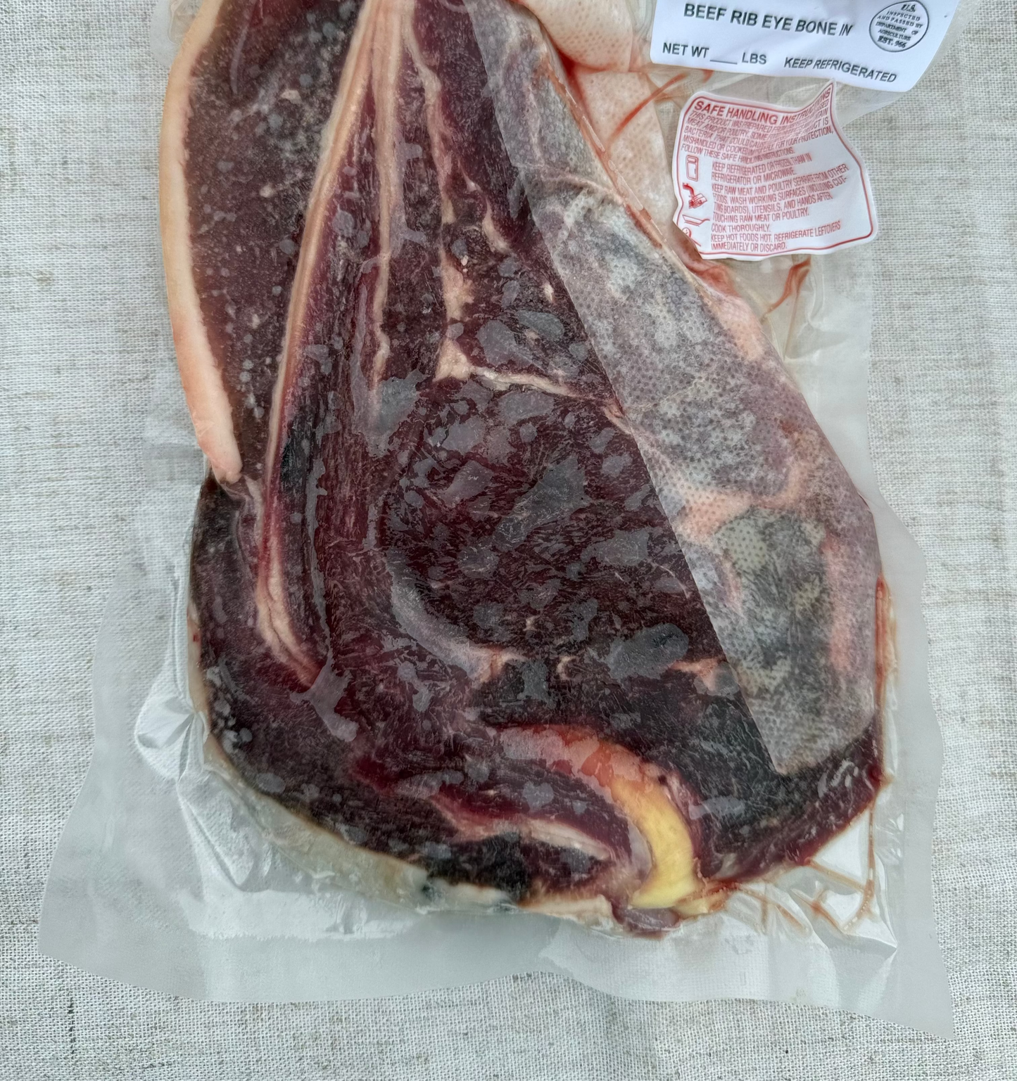 Raw steak with labels on a textured surface