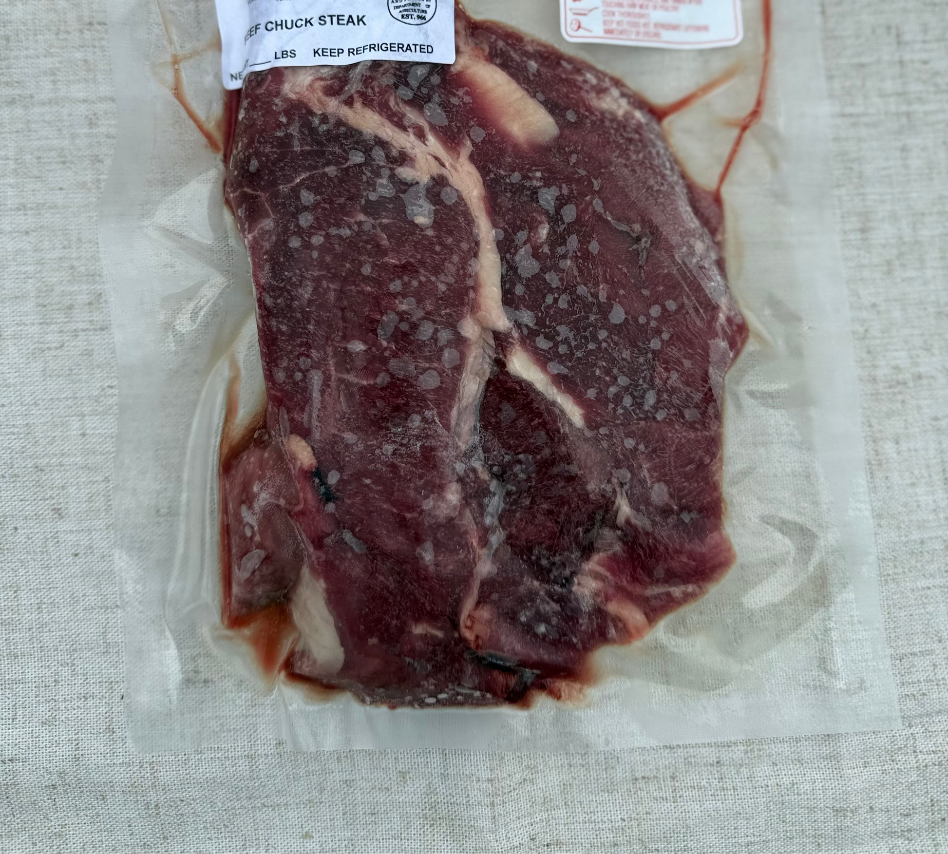 Raw steak in a vacuum-sealed package on a textured surface