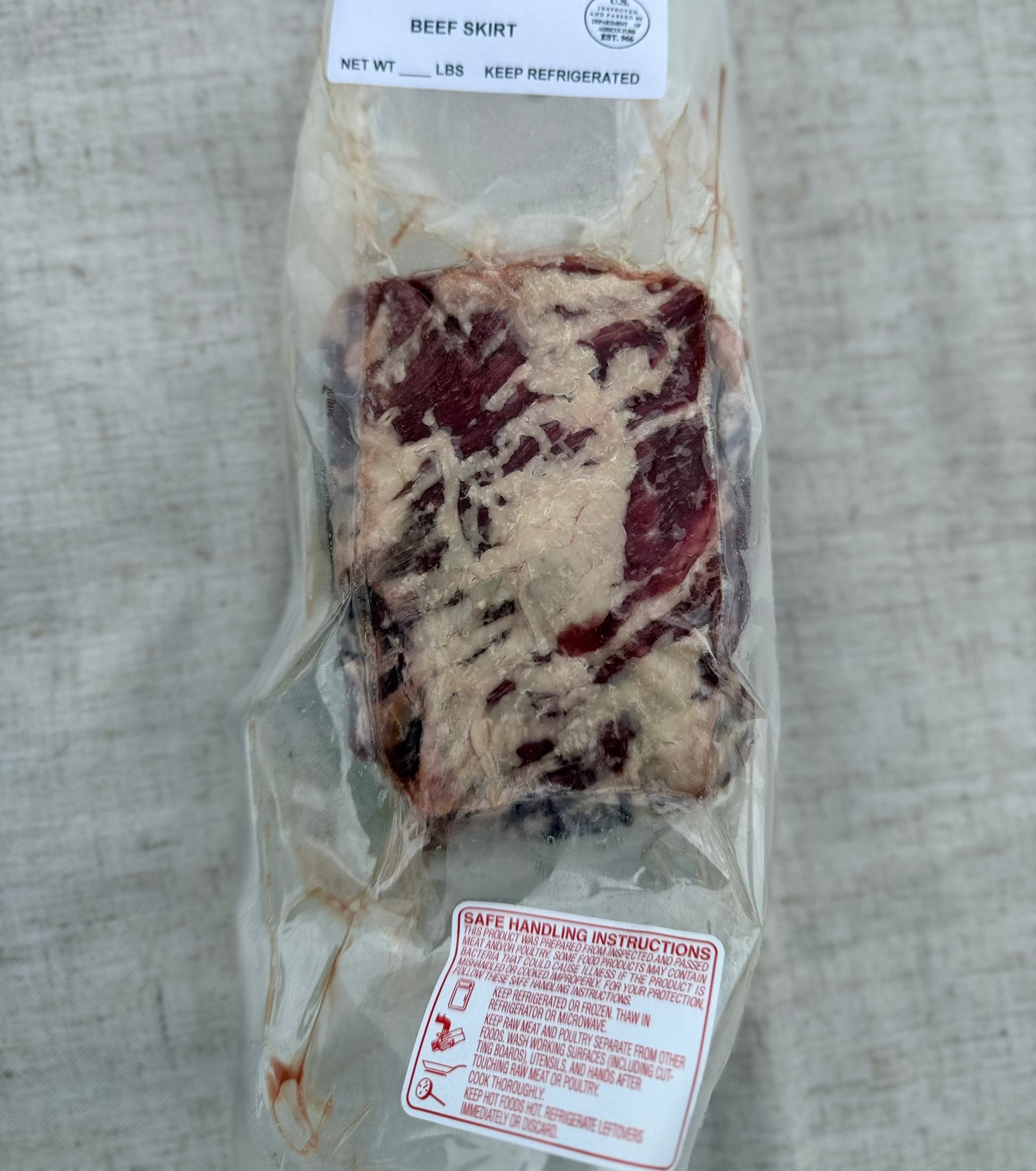Packaged beef skirt with a label on a textured surface