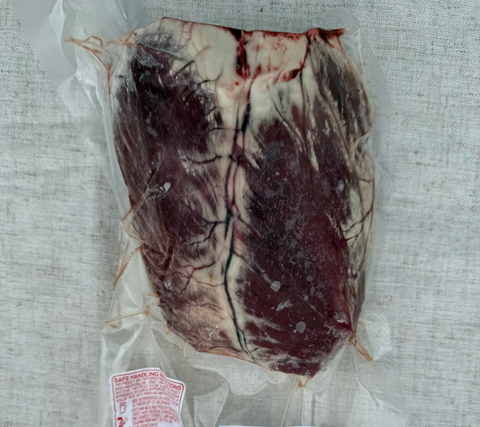 Vacuum-sealed package of raw meat with labels on a textured surface