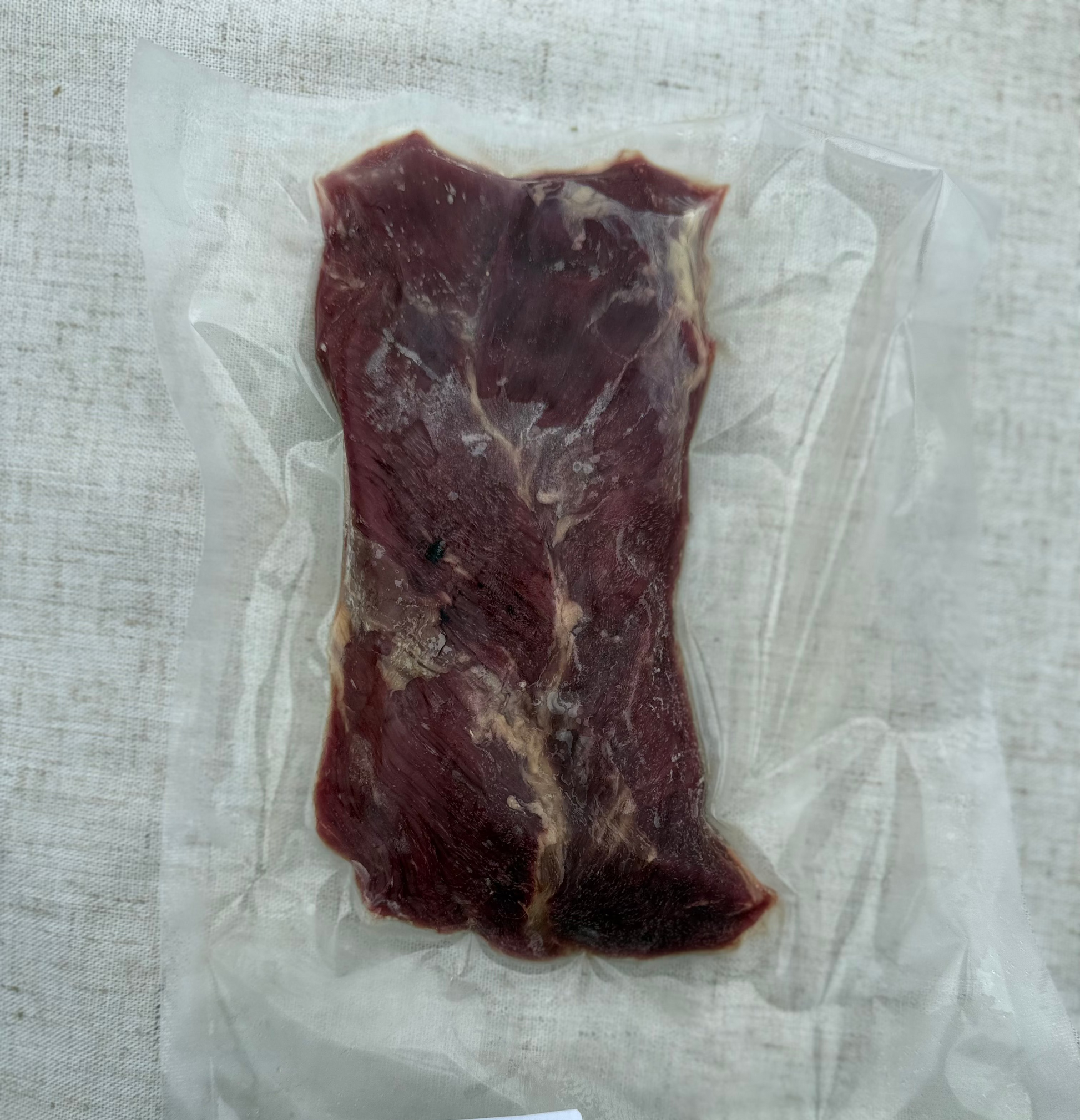 Beef hanging tender in a vacuum-sealed package on a gray surface