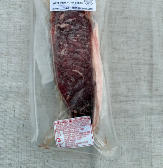 Packaged raw beef New York strip on a textured surface